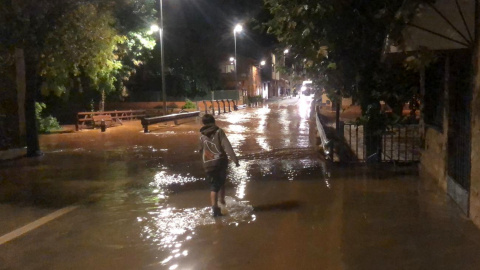 Un nen just abans del pont que dona accés al nucli dels Valentins i per sobre del qual ha saltat l'aigua del barranc