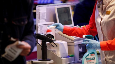 Una cajera desinfecta el datáfono en un supermercado. Foto: EFE/Archivo/Javier Etxezarreta