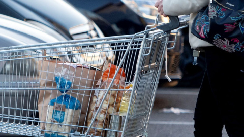 Una mujer sale de un supermercado con un carro de la compra, a 27 de diciembre de 2022, en Mejorada del Campo, Madrid.