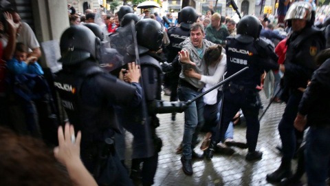 Un hombre intenta proteger a una mujer de los porrazos de agentes antidisturbios de la policía española el 1 de octubre de 2017.