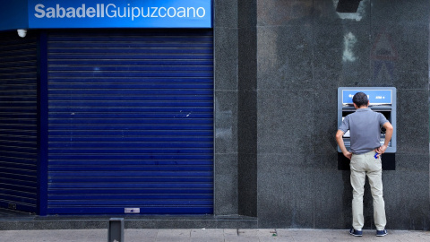 Un cliente opera en un cajero automático de una oficina del  Banco Sabadell en Guernica. REUTERS/Vincent West