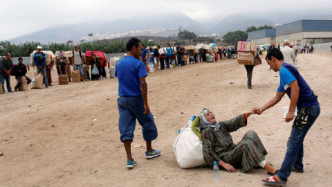 Un hombre ayudando a una de las mujeres al caerse mientras transportaba los materiales / REUTERS -  Youssef Boudlal