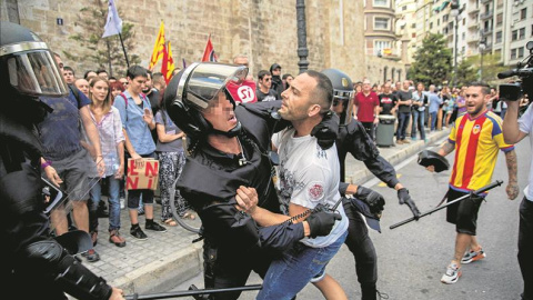 La policía forcejea con uno de los agresores durante la manifestación del 9-O en Valencia. - EFE