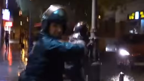 Momento en el que un agente de policía golpea la mano de otro otro agente que se cruza en su camino