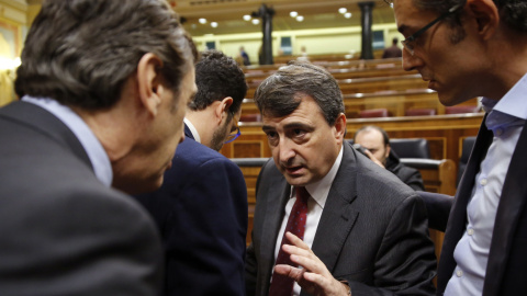 El portavoz parlamentario del PNV, Aitor Esteban, conversa con el portavoz del Grupo Popular, Rafael Hernando, en presencia del diputado socialista Eduardo Madina, durante el pleno del Congreso. EFE/Mariscal