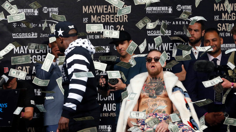 Mayweather arroja un fajo de billetes a la cara de McGregor durante uno de los careos para la promoción del combate.REUTERS/Noah K.Murray