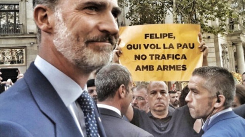 Imagen recogida de Twitter en la que Felipe VI pasa justo por delante de un de un manifestante que sujeta una pancarta con el lema: "Quien hace la paz no trafica con armas".