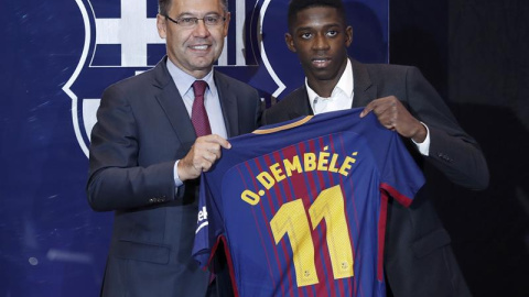 El nuevo fichaje del FC Barcelona, el francés Ousmane Dembélé (d), muestra hoy con el presidente del FC Barcelona, Josep Maria Bartomeu (i) la camiseta que llevará como jugador del equipo azulgrana. EFE/ Andreu Dalmau