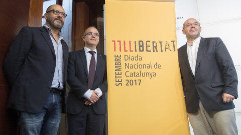 El conseller de la Presidencia y portavoz del Govern, Jordi Turull (c), y el vicepresidente primero del Parlament, Lluís Guinó (d), y el creado artístico del acto de la Diada, Josep María Mestres (i), durante la presentación de los actos instituciona