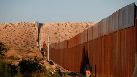 Un hombre pasa por una sección del muro que separa EEUU de México, cerca de Ciudad Juarez. - REUTERS