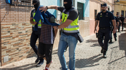 Agentes de la policía llevan detenido a uno de los sospechosos de participar en una red yihadista, en Melilla. REUTERS/Jesus Blasco de Avellaneda