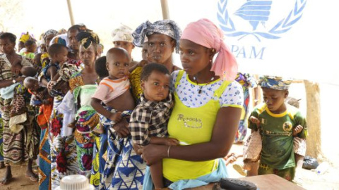 Mujeres y niños hacen cola en un campamento de Burkina Faso. AFP/Ahmed Oioba/Archivo