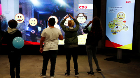 Varios niños observan una pantalla interactiva que muestra las propuestas de la CDU de Angela Merkel, en Berlín. REUTERS/Fabrizio Bensch