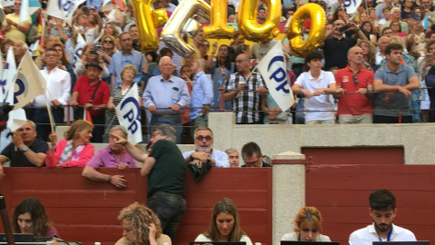 Simpatizantes del PP con globos dorados con las letras del nombre de Feijóo, el domingo en un tendido de la plaza de toros de Pontevedra sobre los escritorios de prensa.