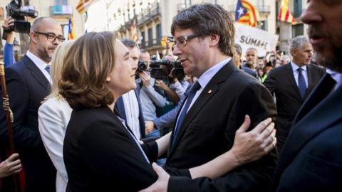 La alcaldesa de Barcelona, Ada Colau (i), saluda al presidente de la Generalitat, Carles Puigdemont (d), durante la concentración de alcaldes en la plaza Sant Jaume de Barcelona, convocada por la AMI y la ACM para protestar por las actuaciones de la Fisc