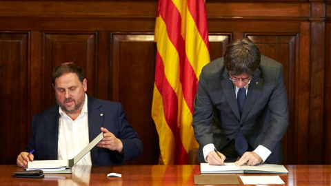 El presidente de la Generalitat, Carles Puigdemont, acompañado por el vicepresidente Oriol Junqueras, firma la convocatoria de referéndum. - EFE