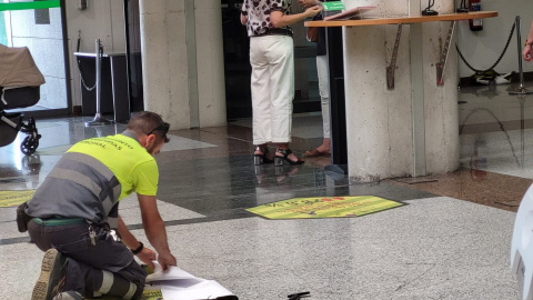 Uno de los operarios municipales retira las señaléticas de violencia machista en el 'hall' del Ayuntamiento de Alcobendas.