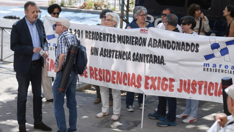 El exconsejero de Políticas Sociales Alberto Reyero (i) conversa con un hombre que participa en una concentración para pedir justicia por los residentes fallecidos durante el Covid, medios a su llegada a testificar en los Juzgados de Plaza de Castilla, 