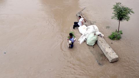 13/07/2023.- Un indio rescata a un perro de una zona inundada en una zona baja del río Yamuna en Nueva Delhi, India, a 13 de julio de 2023.