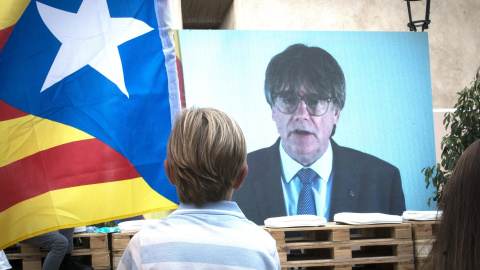 Un niño observa la intervención telemática de Puigdemont en el mitin central del partido JxCAT, a 16 de julio de 2023, en en Amer, Girona, Catalunya (España). Junts per Catalunya ha elegido la ciudad natal del expresidente de la Generalitat y de la fo