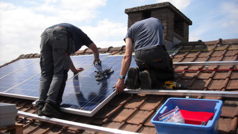 Dos instaladores colocan placas solares en el edificio de una vivienda, en una imagen de archivo