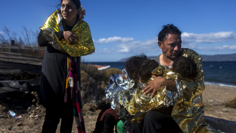 Una familia siria se protege del frío en la playa de la isla griega de Lesbos, antes de llegar al campo de refugiados de Kara Tepe.- JAVI JULIO / NERVIO FOTO