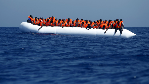 Inmigrantes en la embarcación de goma en la que han atravesado el Mediterráneo esperan a ser rescatados frente a la costa de Libia. REUTERS/Darrin Zammit Lupi