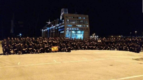 La Policía Nacional posando, con bandera de España incluida, al lado del crucero en el que se alojan en Barcelona. (@PortuariosCNT)