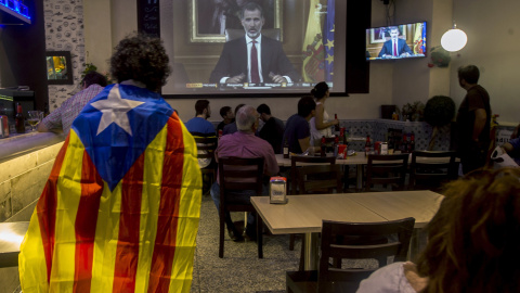 Varias personas miran el discurso del rey Felipe VI en un bar en Barcelona, al final de la jornada de paro general en protesta por la actuación policial durante el referéndum del 1-O. EFE/Quique García