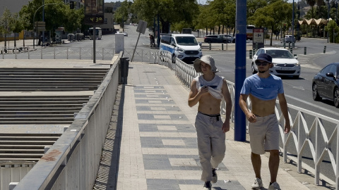 Un grupo de turistas se protegen con sombrillas del sol en Sevilla, España, a 30/07/2023. David Arjona / EFE.