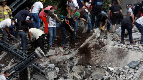 Varias personas buscan supervivientes entre los escombros de un edificio caído tras el terremoto en Ciudad de México. - REUTERS