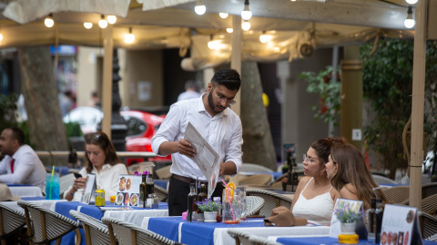 Un camarero atiende a una mesa en las Ramblas, a 15 de junio de 2022, en Barcelona.