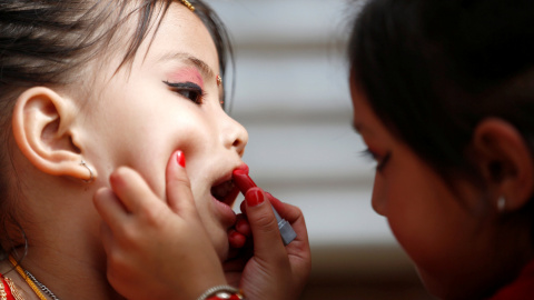 Una niña le pinta los labios a su amiga. REUTERS/ Navesh Chitrakar