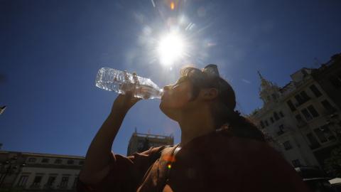 31/07/2023.-Una mujer se refresca bebiendo agua en el centro de Córdoba donde se ha dado aviso naranja por altas temperaturas.