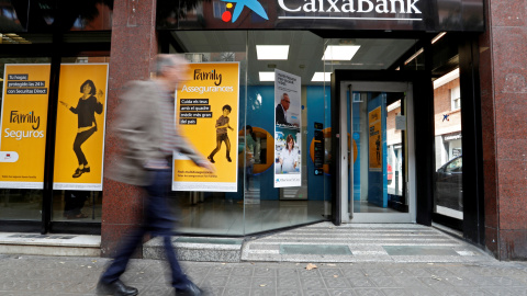 Un hombre pasa junto a una sucursal de Caixabank en Barcelona. REUTERS/Yves Herman