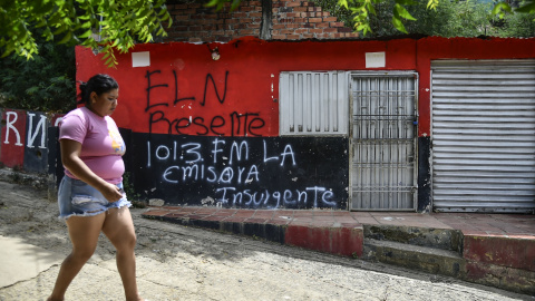 Una mujer pasa frente a una casa con un grafiti de la guerrilla del ELN cerca de Cacuta, Colombia, a 4 de julio.