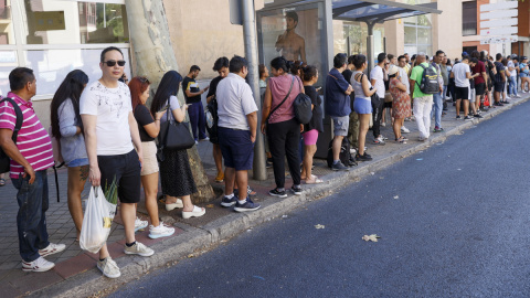 Numerosas personas guardan cola para subir al autobús tras el colapso de la red de Cercanías de Madrid, a 3 de agosto de 2023