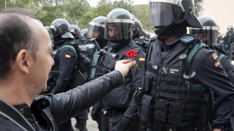 Un hombre ofrece un clavel a un agente de la Guardia Civil en el centro de votación de Sant Julià de Ramis (Girona) donde inicialmente tenía previsto votar el presidente de la Generalitat, Carles Puigdemont, en el referéndum independentista del 1-O./ 