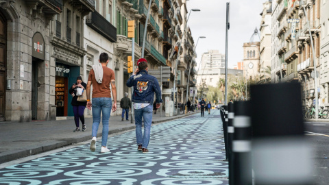 Pla general de dos homes caminant pel carrer Pelai, amb l'espai per a vianants pintat amb panots blaus, en una imatge d'arxiu