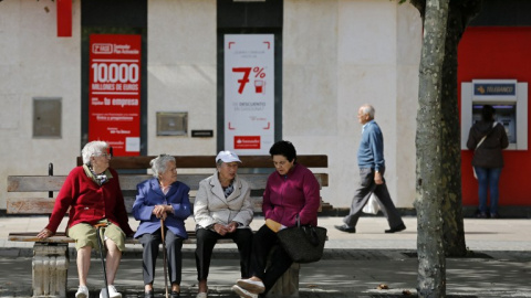 Varios pensionistas sentados en un banco cerca de una oficina bancaria en la localidad burgalesa de Briviesca. AFP / César Manso