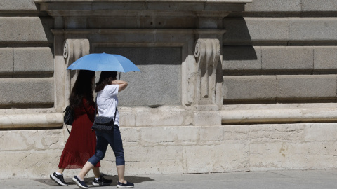 06/08/2023.- Dos mujeres se protegen del sol en Madrid este domingo .