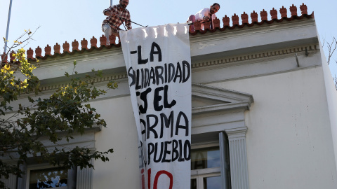 Empleados de la embajada española en Atenas retiran la pancarta "La solidaridad es el arma del pueblo". /REUTERS