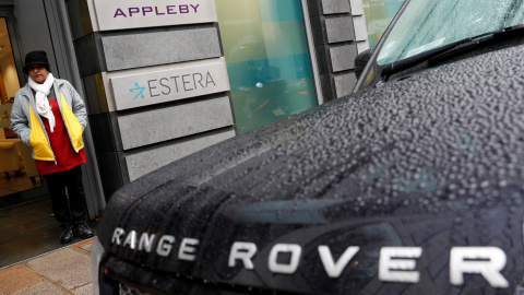 Una mujer se resguarda de la lluvia en la entrada de las oficinas de Appleby en Jersey.REUTERS/Darren Staples