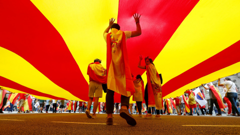 Varias personas bajo una gigantesca bandera catalana en la marcha en Barcelona por el día de la Fiesta Nacional. REUTERS/Gonzalo Fuentes