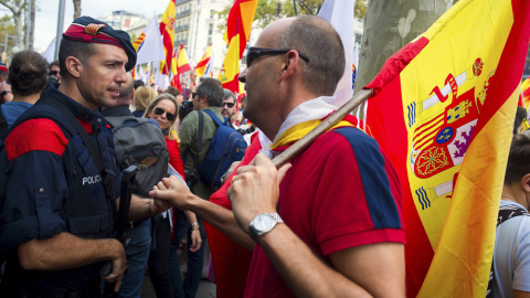 Un hombre con la bandera de España saluda a un mosso de esquadra durante la manifestación convocada por Societat Civil Catalana, Espanya i Catalans y otras entidades contrarias a la independencia con motivo del Día de la Fiesta Nacional. EFE/Andreu Dal