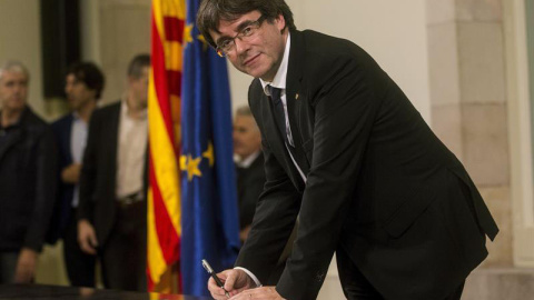 Puigdemont firma el documento de adhesión a la República catalana después de comparecer ante el pleno del Parlament para trasladar los resultados de la jornada del 1-O. | QUIQUE GARCÍA (EFE)