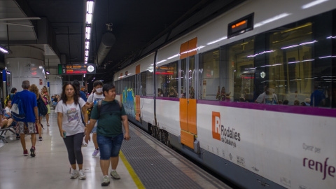 11/08/2023 Viajeros al lado de un tren en uno de los andenes de la estación de Sants