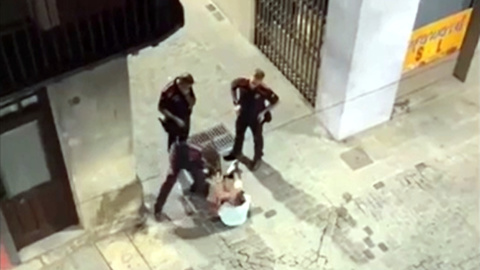 Captura del vídeo del moment en què l'agent dels mossos venta una bufetada a l'home assegut al mig del carrer a Olot