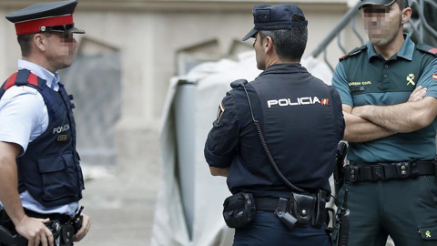 Un mosso, un policía nacional y un guardia civil vigilan el exterior del edificio de la Delegación del Gobierno en Catalunya, durante la reunión de coordinación de los cuerpos de seguridad sobre el 1-O. EFE/Andreu Dalmau