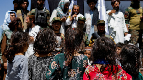 Niñas afganas observan a simpatizantes talibanes en el segundo aniversario de la caída de Kabul en una calle cerca de la embajada de EEUU en Kabul